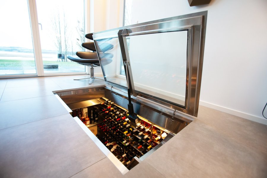 Bespoke wine cellar built into the floor with elegant glass door and wine bottles