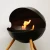 Free-standing circular bioethanol fireplace with three legs of oak wood